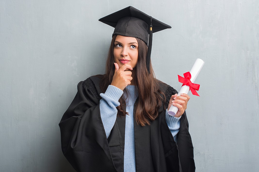 woman wearing a graduation robe and holding a master degree