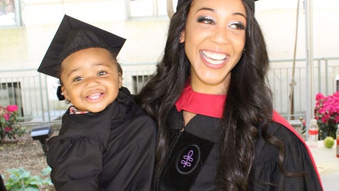 woman and baby are smiling and dressed in graduation gowns