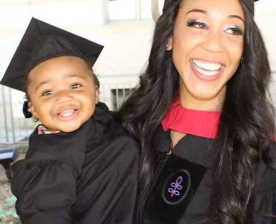 woman and baby are smiling and dressed in graduation gowns