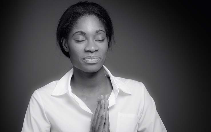 woman praying with her eyes closed and head bowed